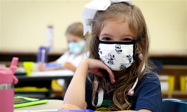 girl smiles while wearing mask